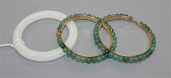A Chinese white jade bangle and two green stone bangles